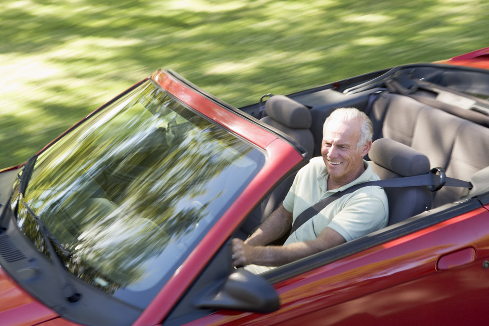 A man driving a red convertible car